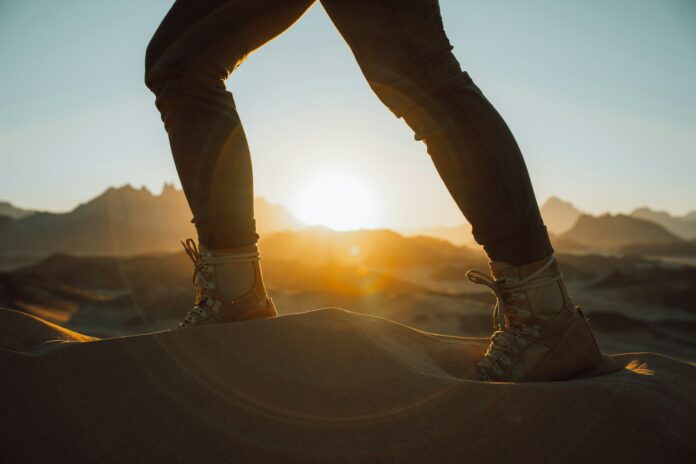 Photo by NEOM a person standing on top of a sand dune