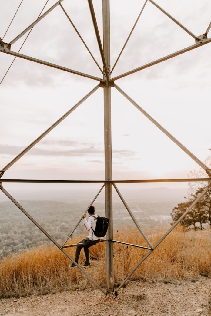 Photo by Hannah Busing man in black jacket sitting on brown grass field during daytime