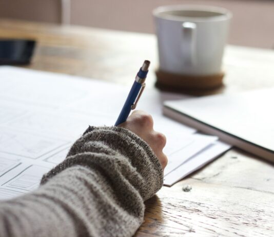 재무덕후가 알려주는 경제와 친해지는 방법 person writing on brown wooden table near white ceramic mug