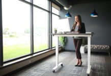 MZ세대, ‘장시간 앉기’ 탈출 중…‘액티브 라이프스타일’로 전환 가속 a woman standing at a desk in front of a window