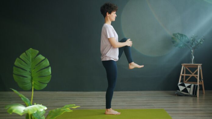 Photo by Vitaly Gariev Woman practicing yoga on a green mat indoors.
